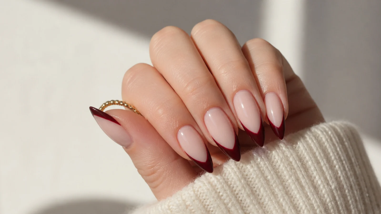 Long almond nails with deep burgundy tips over a sheer nude base in a modern French
