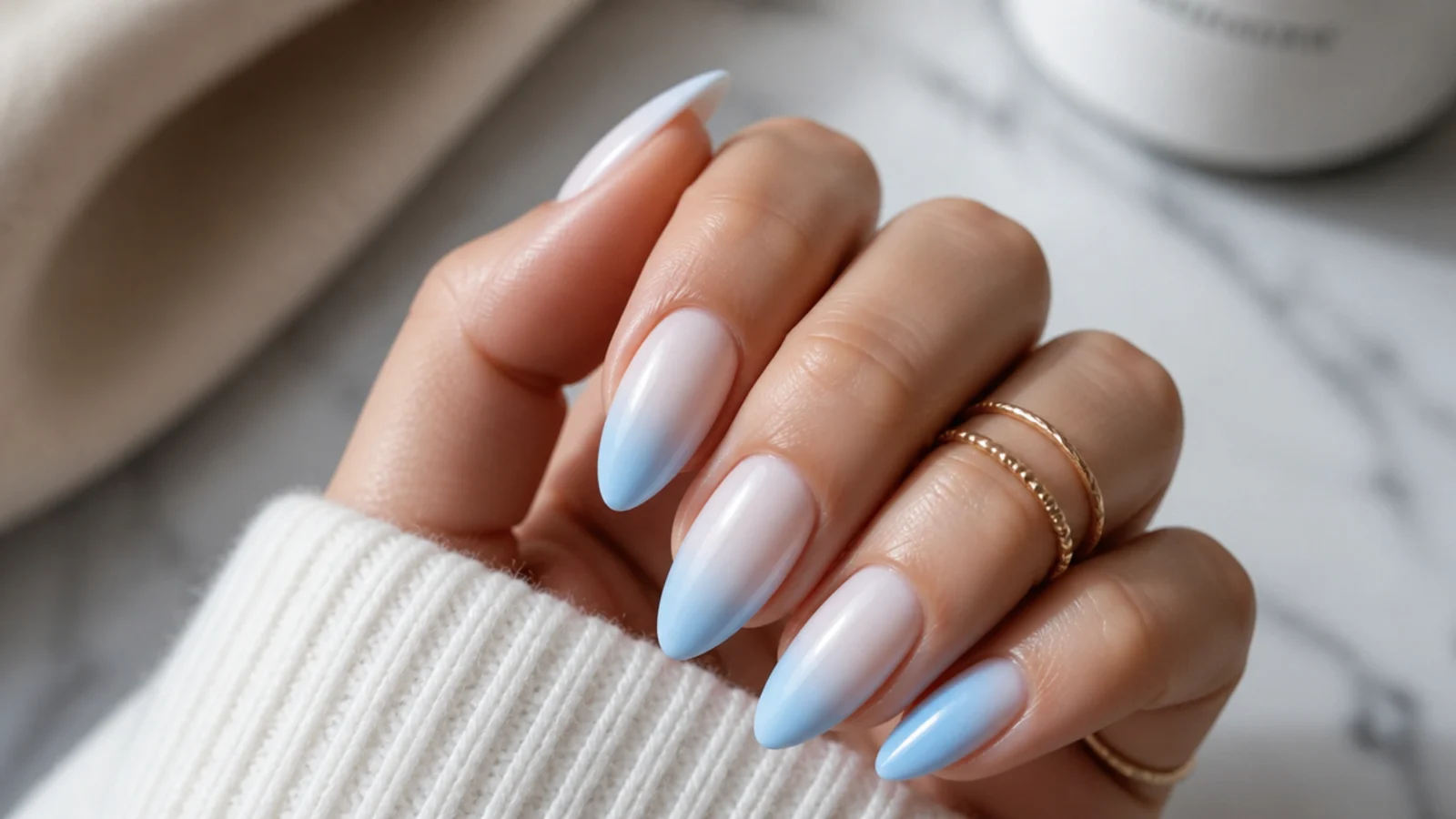 Medium almond nails with a soft baby blue to white ombre fading toward the cuticle