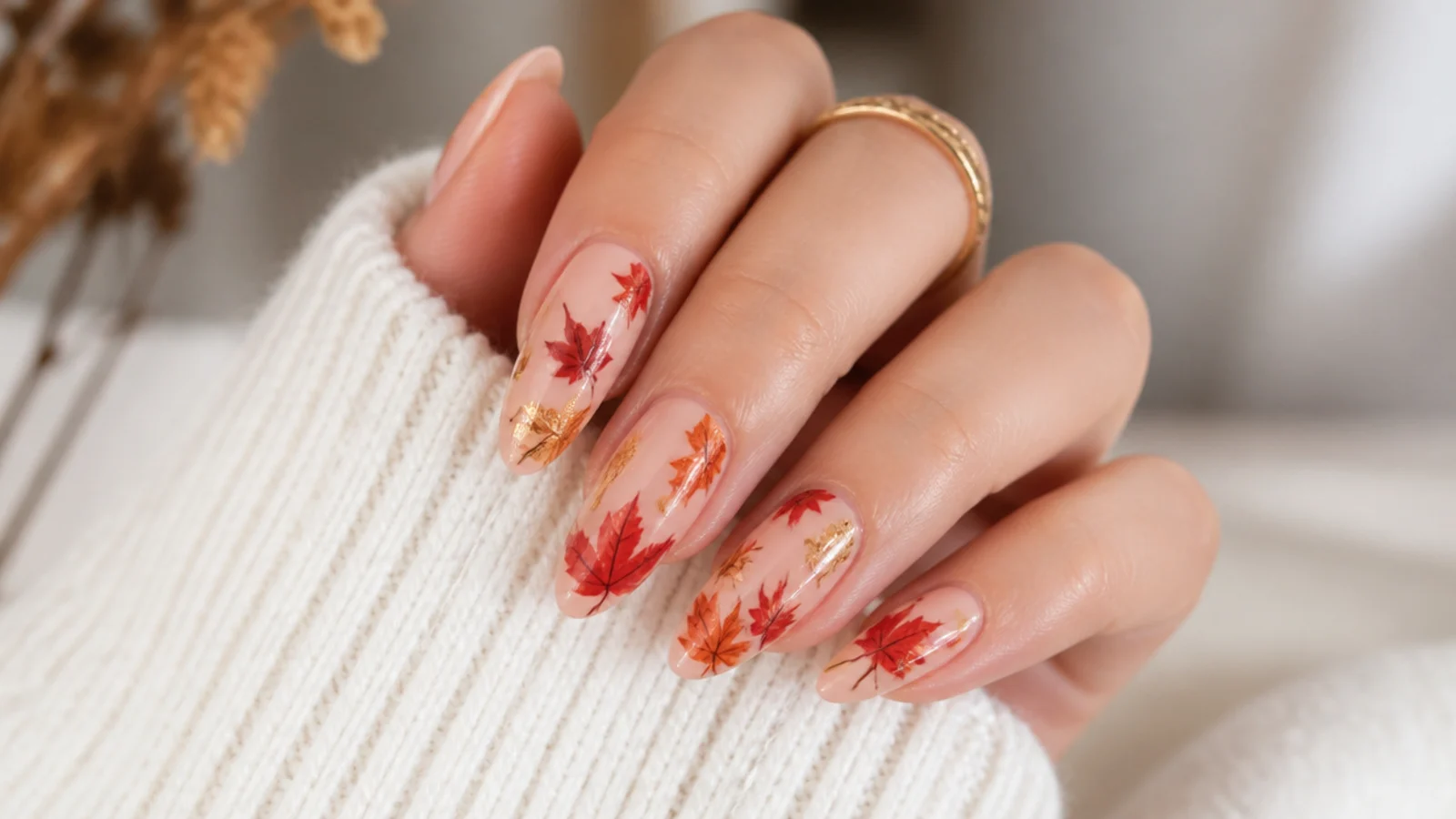 Medium almond nails with hand-painted autumn leaves in red orange and bronze on a nude base