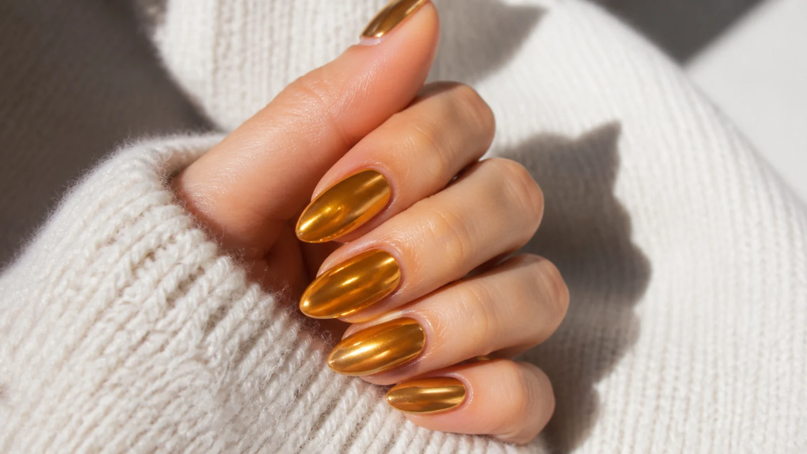 Medium almond nails in warm golden amber chrome with a honey-toned metallic sheen