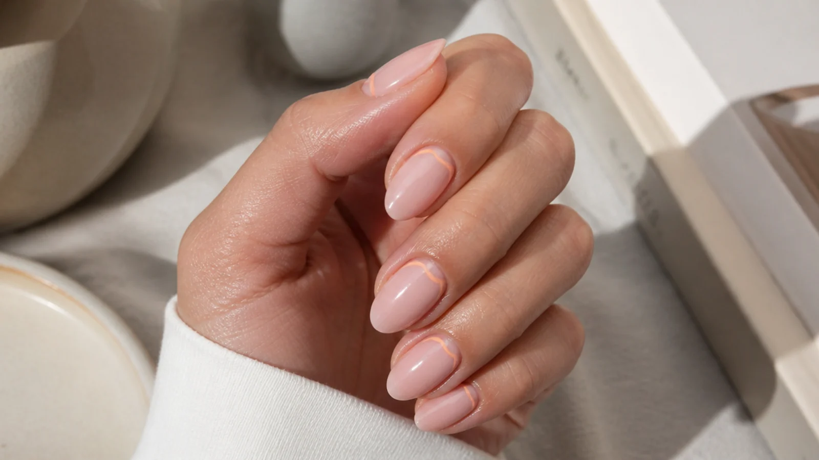 Short almond nails with a thin reverse French line painted at the cuticle in soft peach