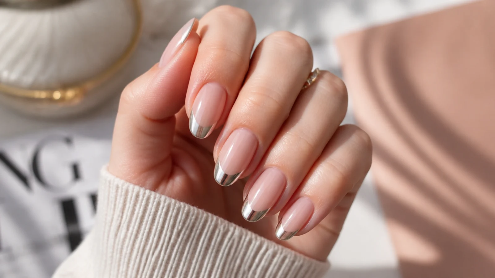 Medium almond nails with a mirror silver chrome French tip over a sheer nude base