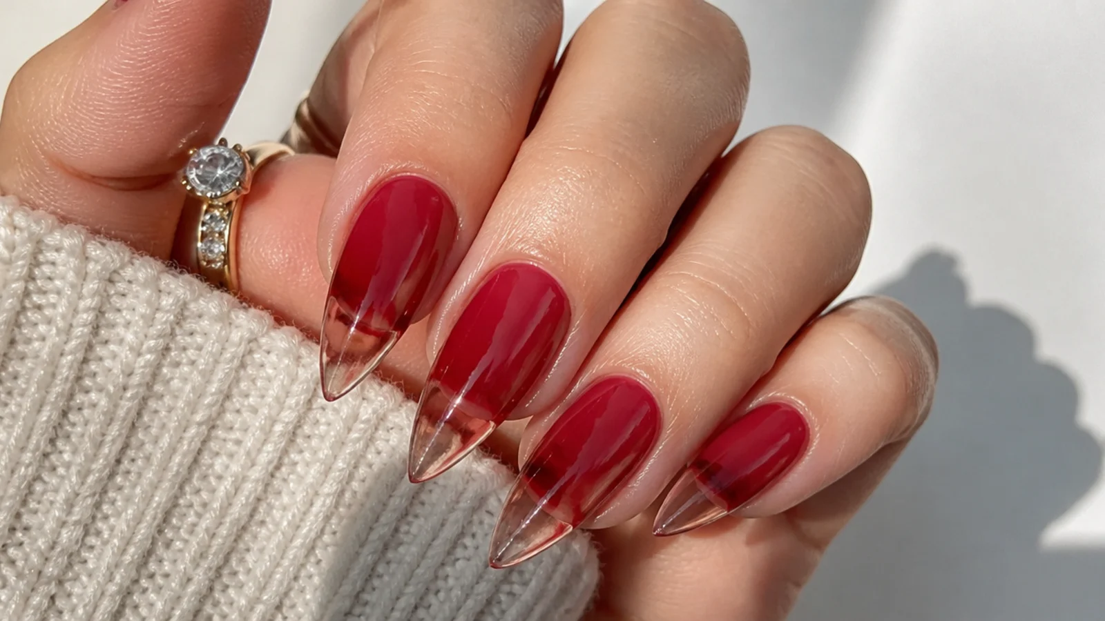 Translucent cherry jelly stiletto nails with the natural nail visible through the point