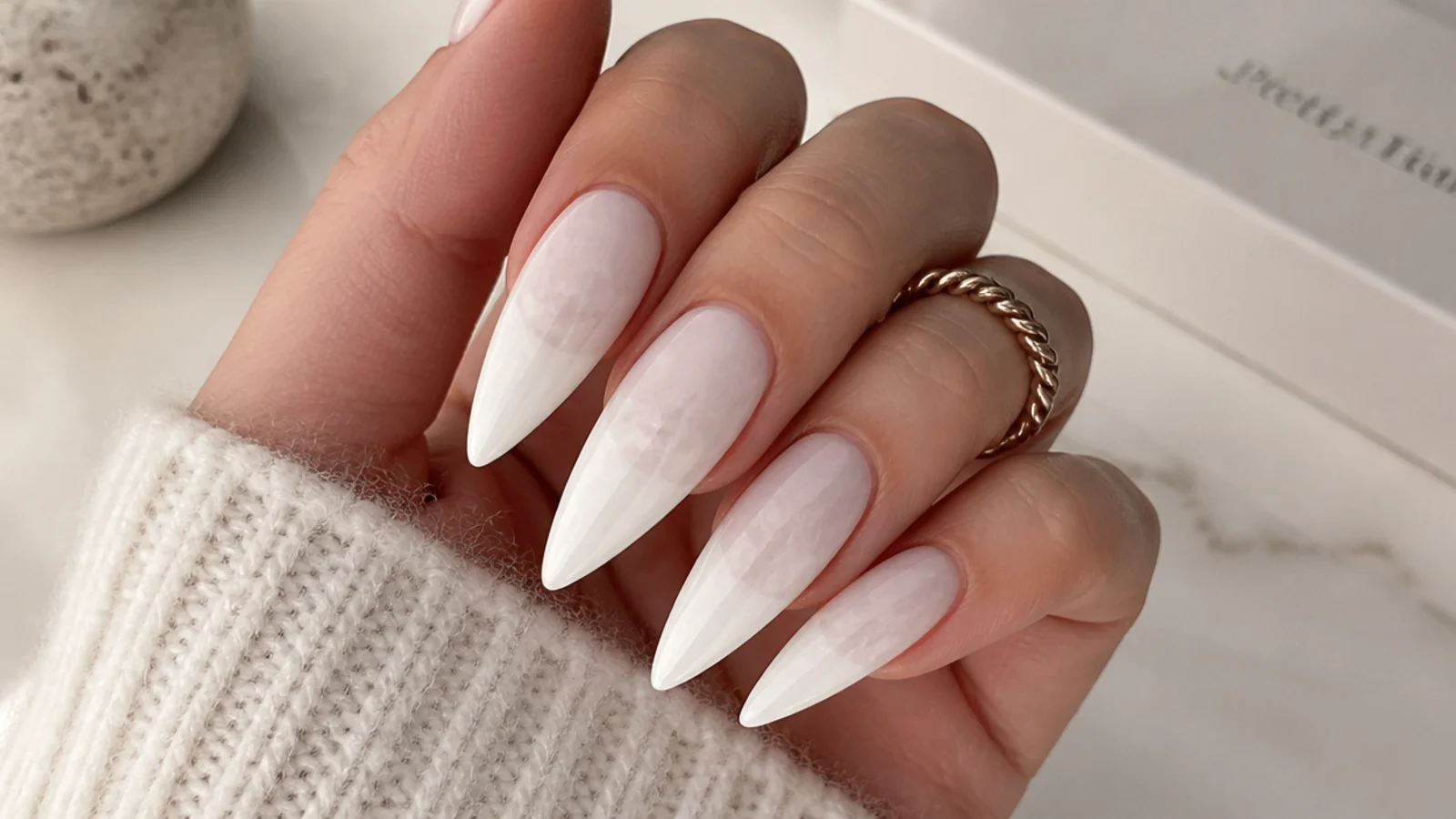 Long milky white stiletto nails with a soft cloudy finish and sharp point