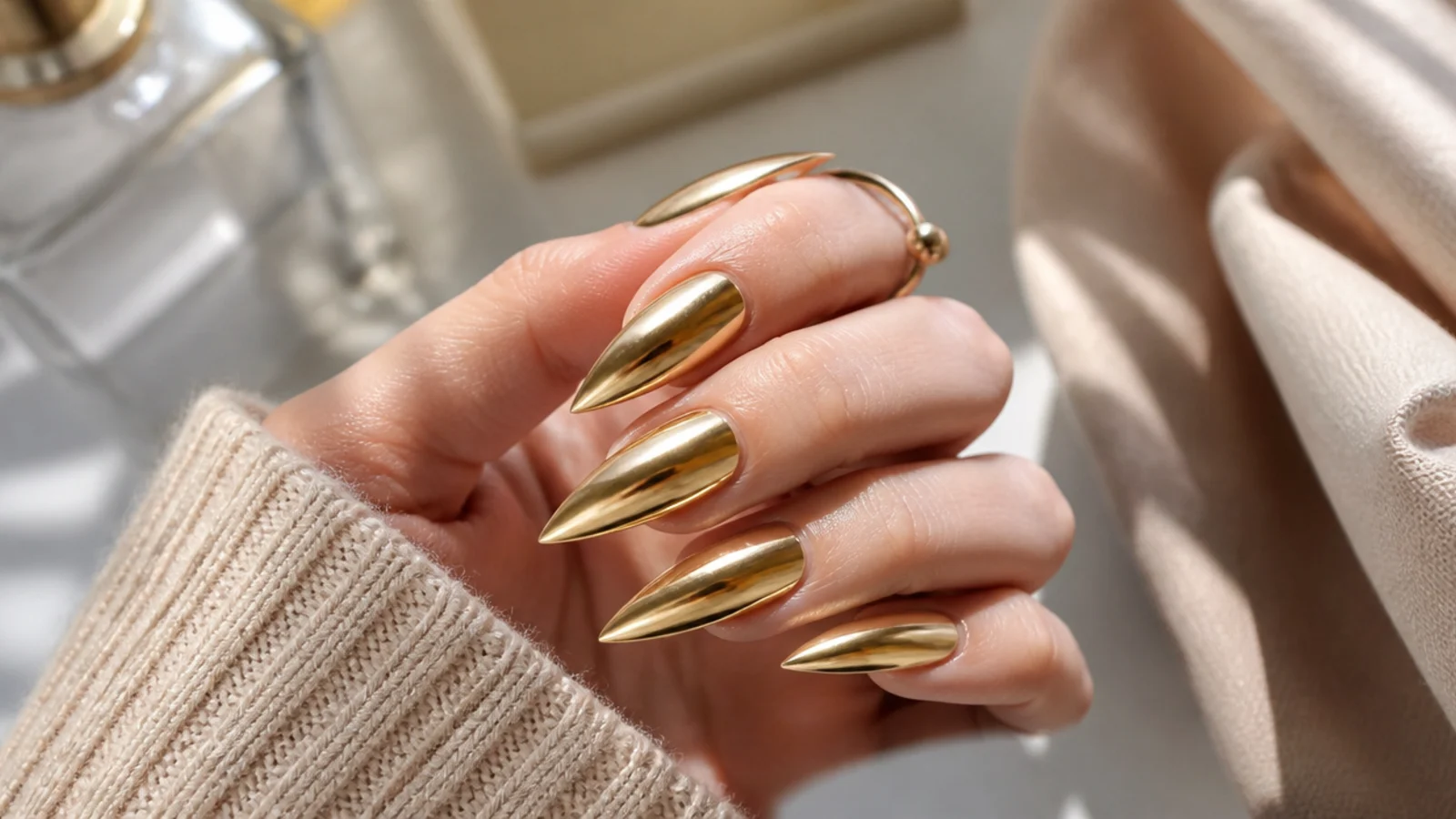 Long gold chrome stiletto nails with a warm metallic mirror finish