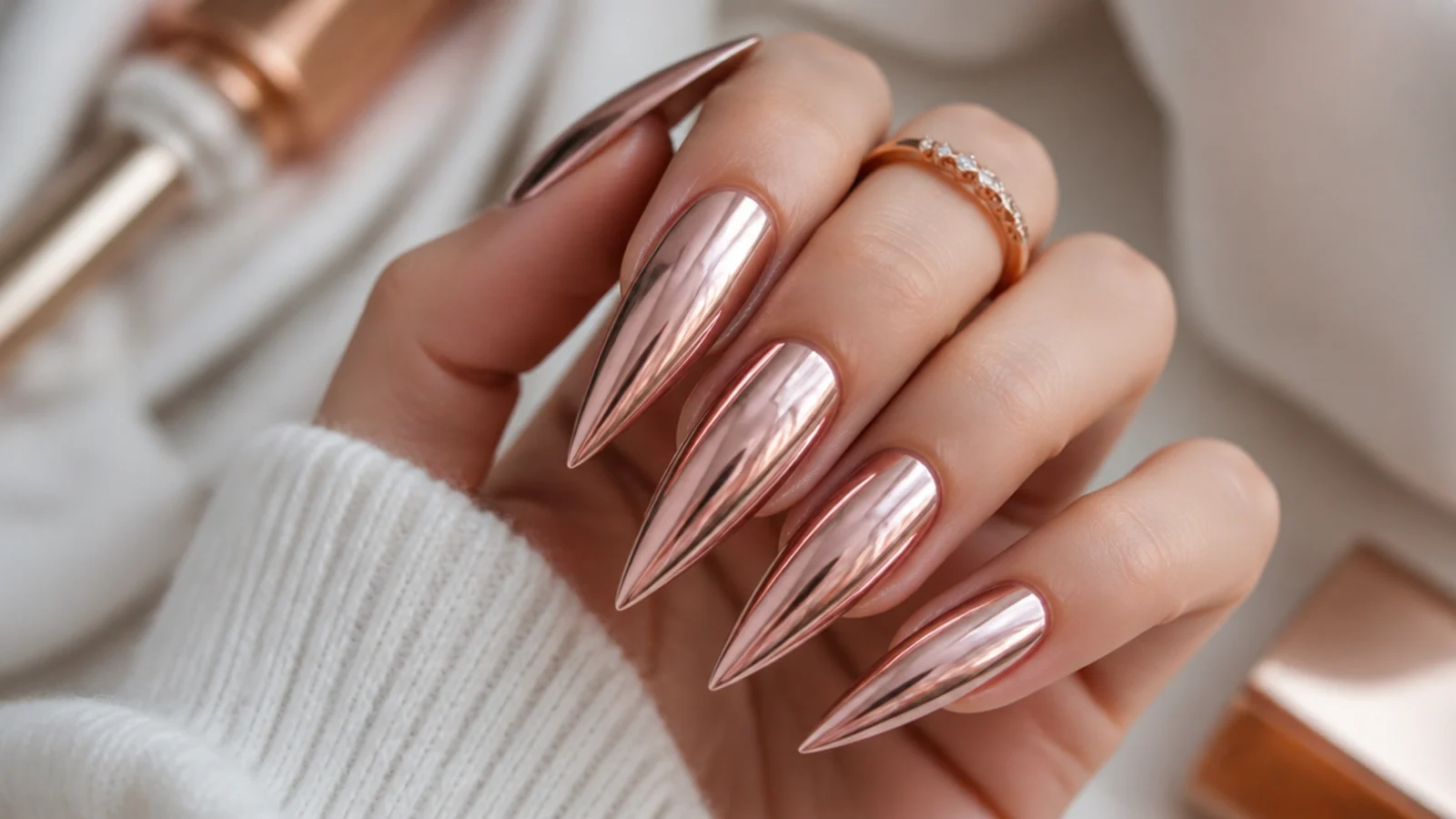 Long rose gold chrome stiletto nails with a warm pink metallic sheen