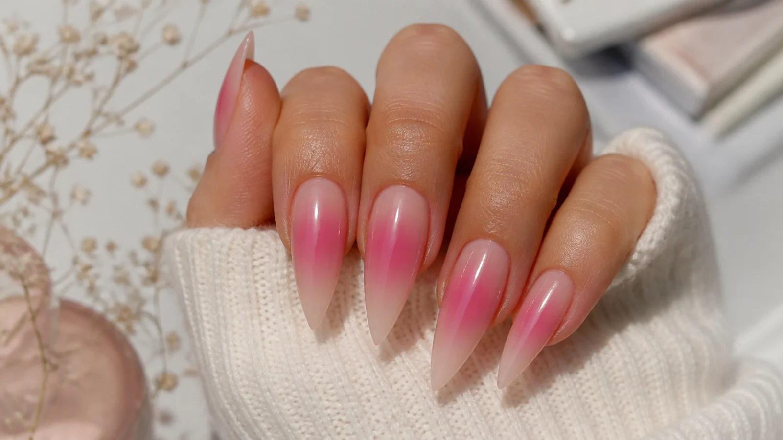 Stiletto nails with a pink aura halo airbrushed into the center over a nude base