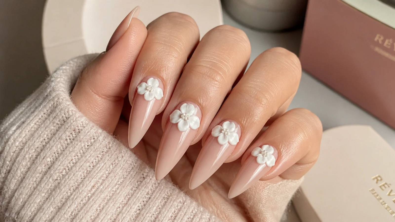 Long stiletto nails with raised white 3D acrylic flowers sculpted near the cuticle
