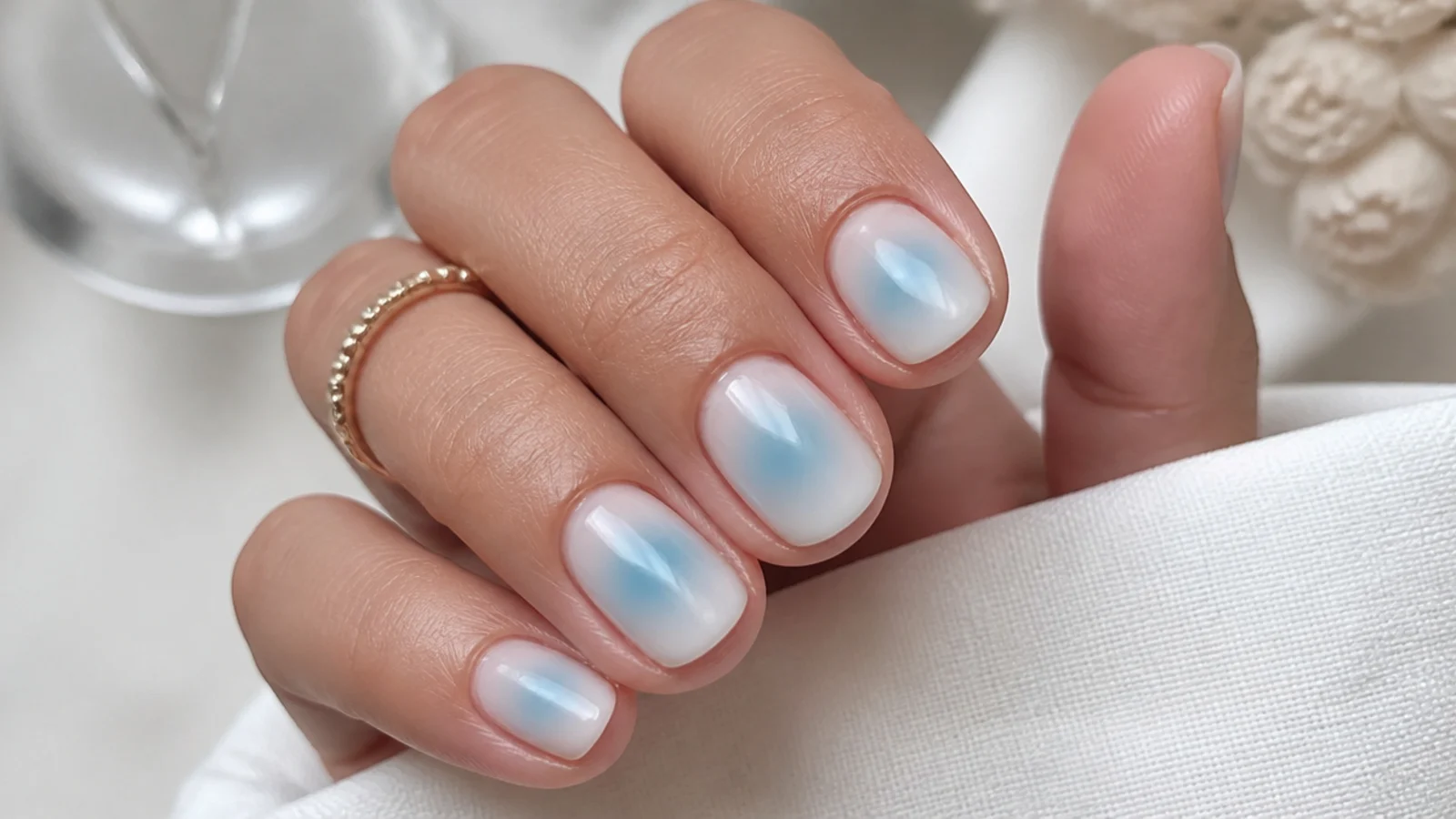 Short summer nails with an aqua blue aura halo airbrushed into the center of a pale base