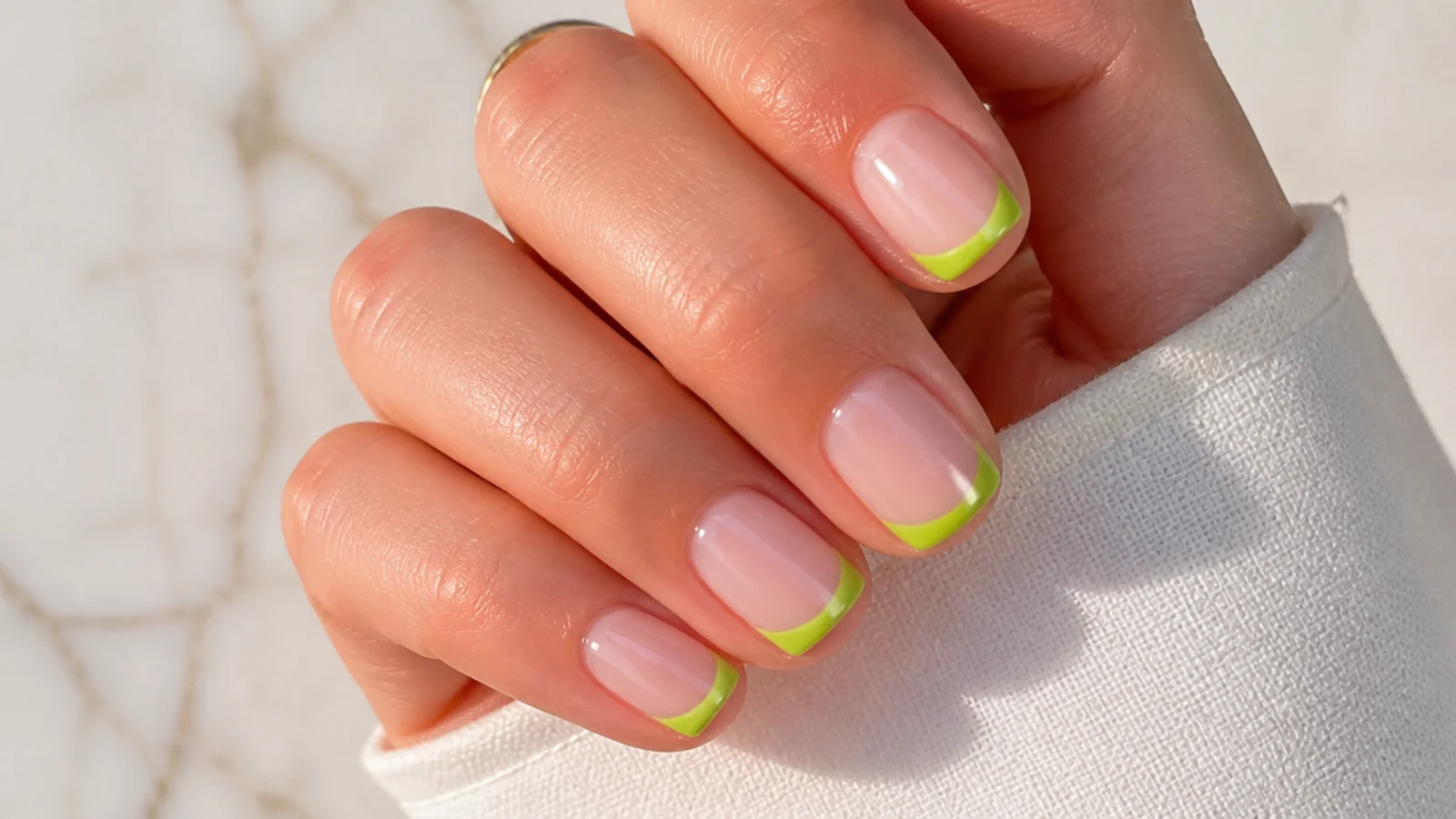 Short summer nails with lime green French tips over a sheer nude base