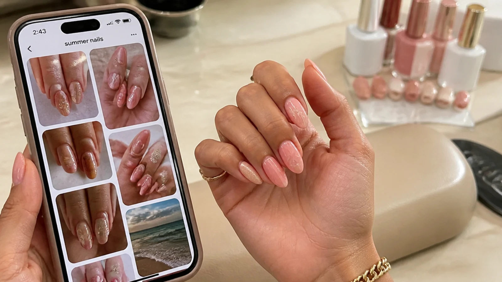 Phone showing summer nail reference photos held beside a hand at a nail salon table