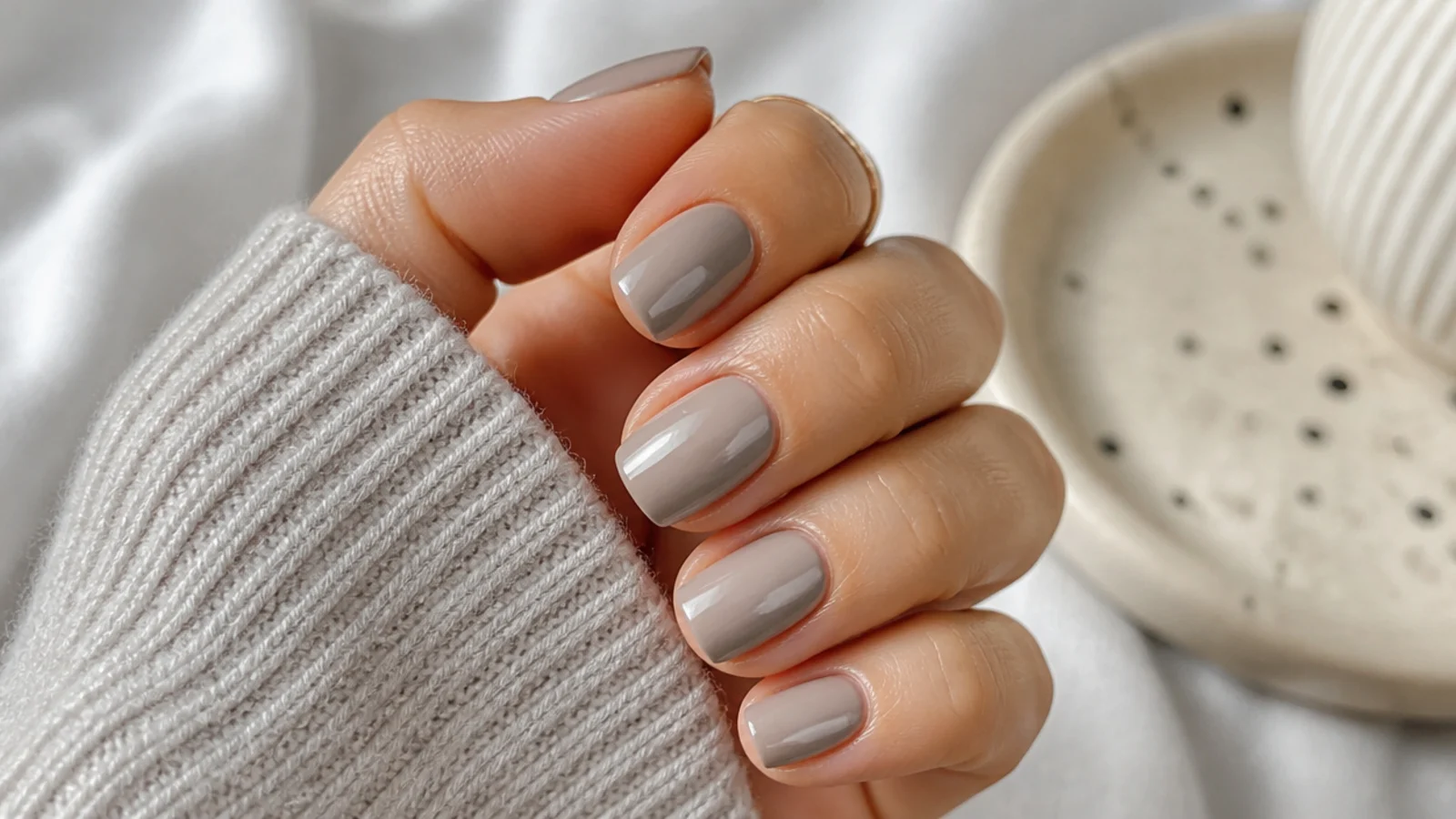 Short greige acrylic nails in a squoval shape with a cool gray beige opaque finish