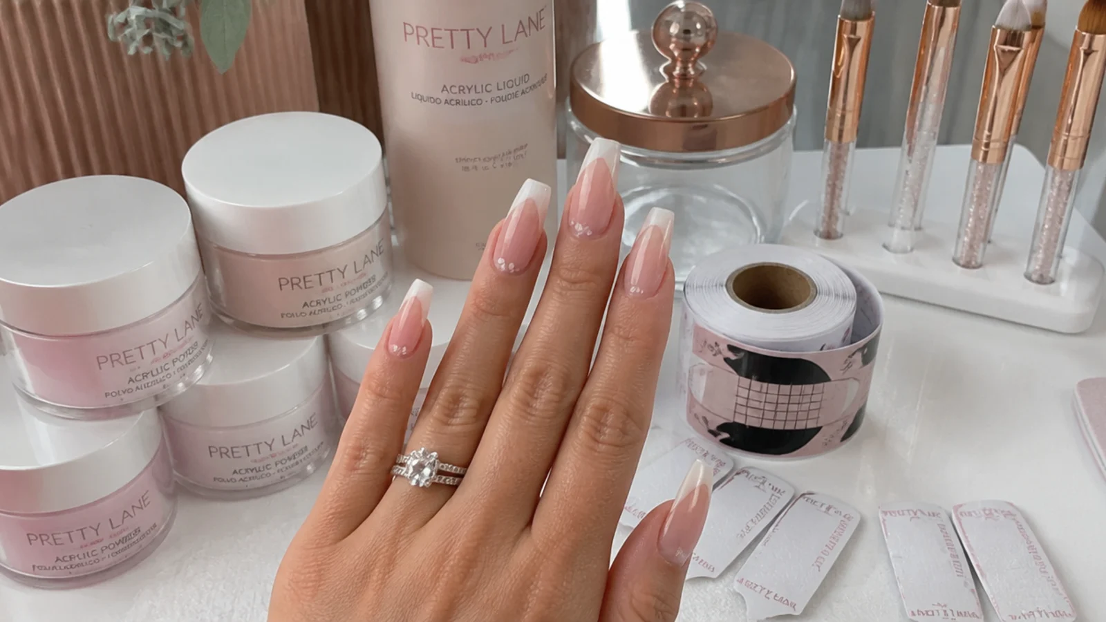 Nail salon station with acrylic powder jars, monomer, brushes and forms laid out for a full set
