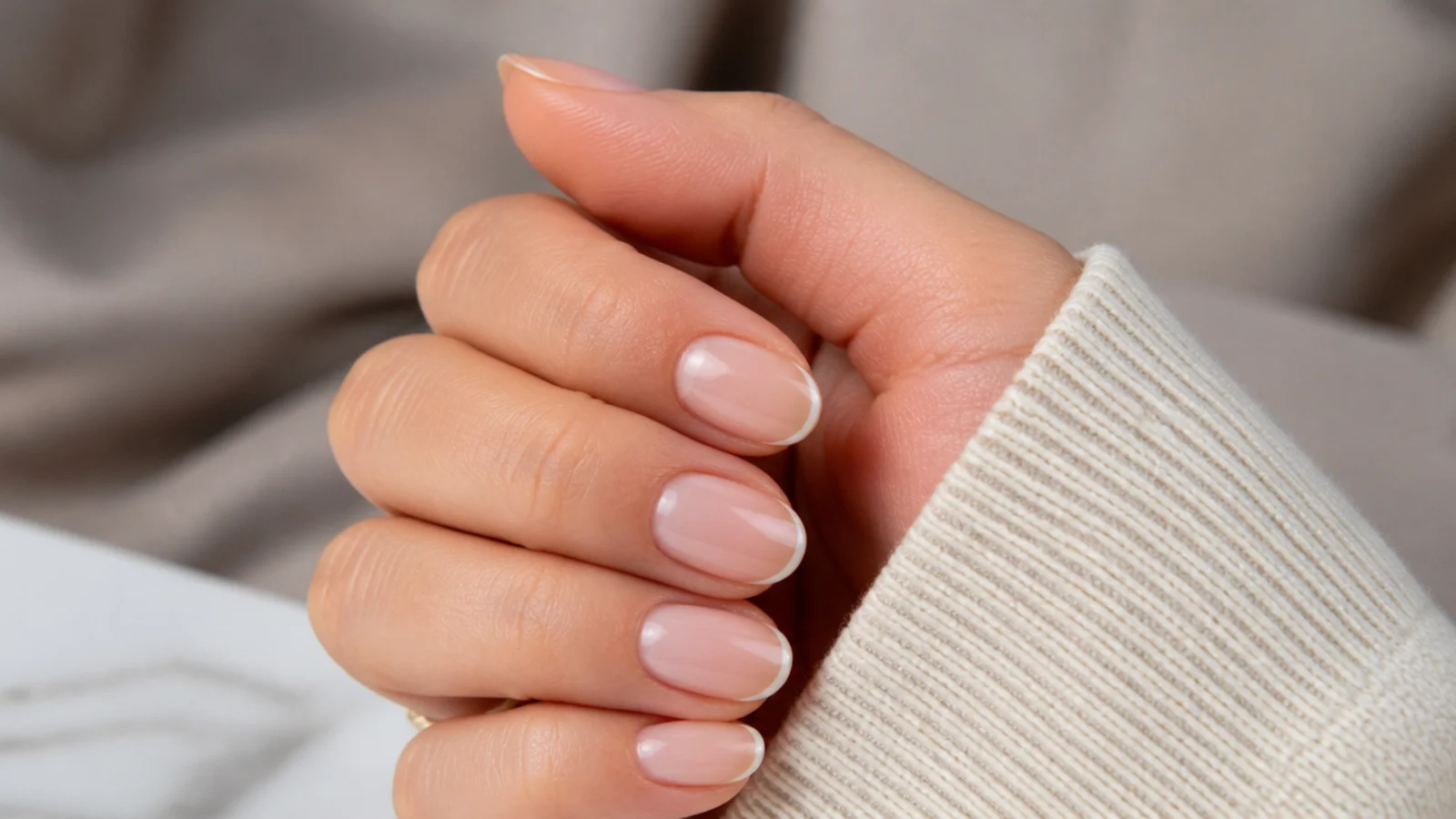 Short almond nails with a hairline white micro French tip painted along the curved edge