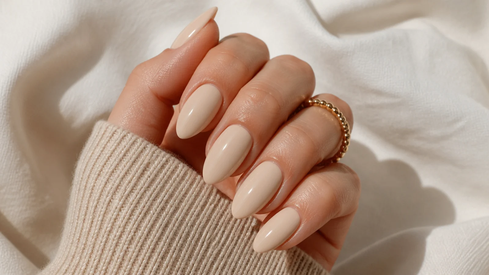 Opaque soft beige almond nails in a creamy single tone with medium length points