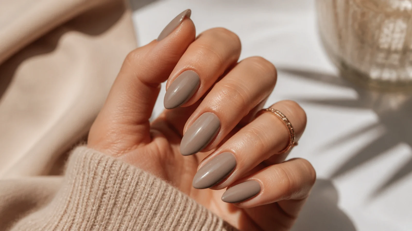 Greige almond nails in a warm gray beige shade with a glossy finish and medium length