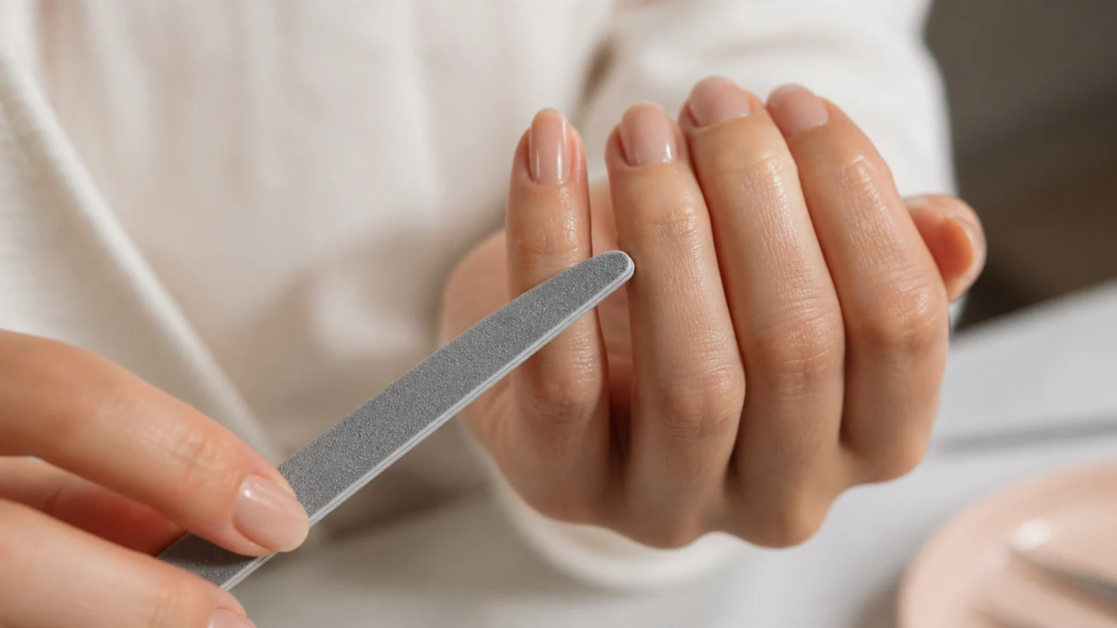 Hand filing an almond nail shape with a 180 grit file angled in from the sidewall toward the tip