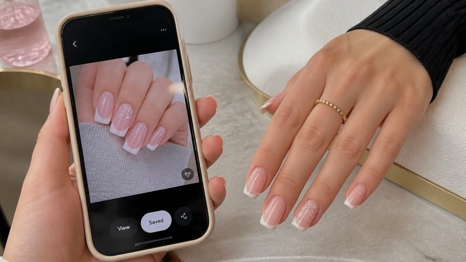 Phone showing a saved classy nail photo held next to a hand at a nail salon table