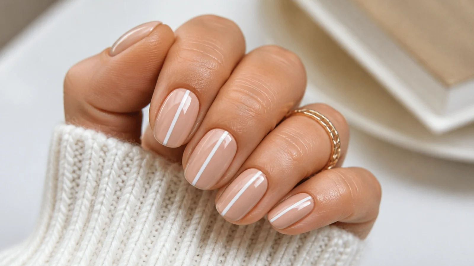 Beige nude nails with a single skinny white stripe painted down the center of the nail