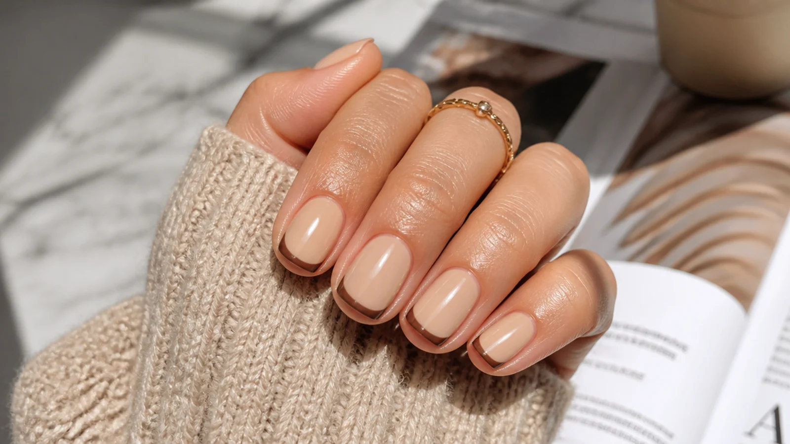 Short nails with mocha brown French tips over a warm beige base