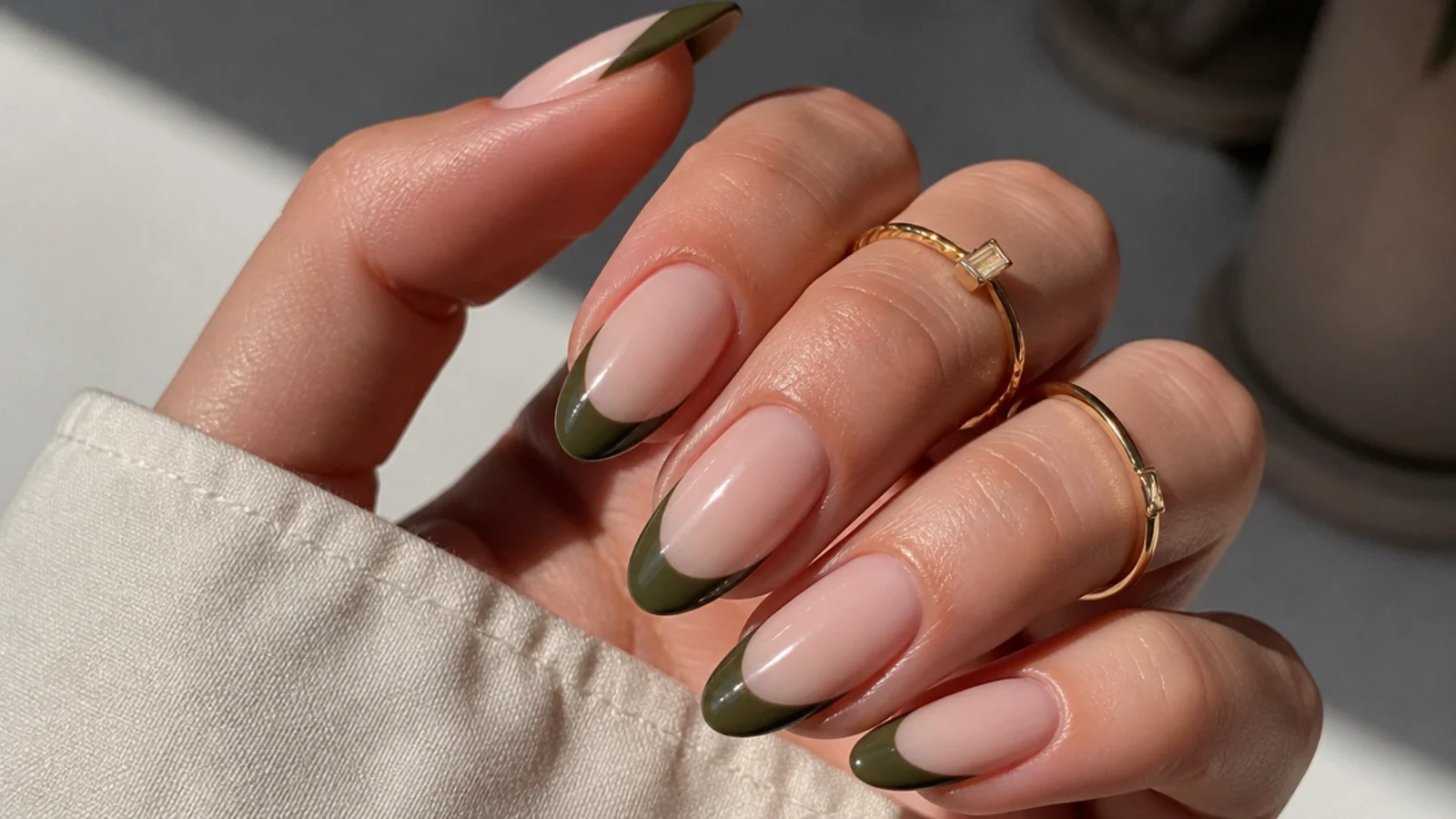 Dark olive green french tip nails over a nude base on almond nails