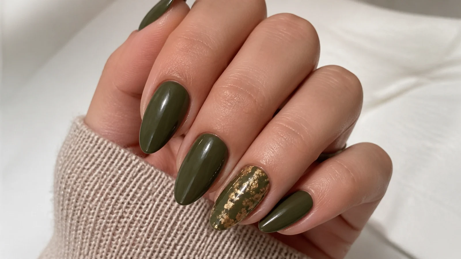Dark olive green nails with torn gold foil flecks on an accent nail
