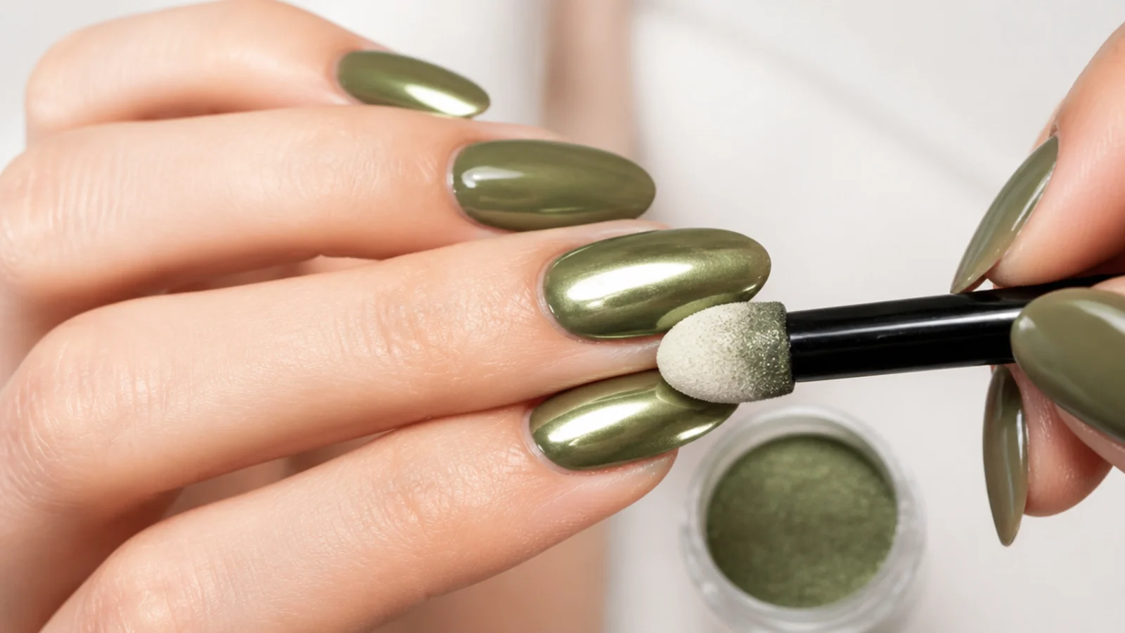 Chrome powder being buffed over cured olive green gel for a metallic finish