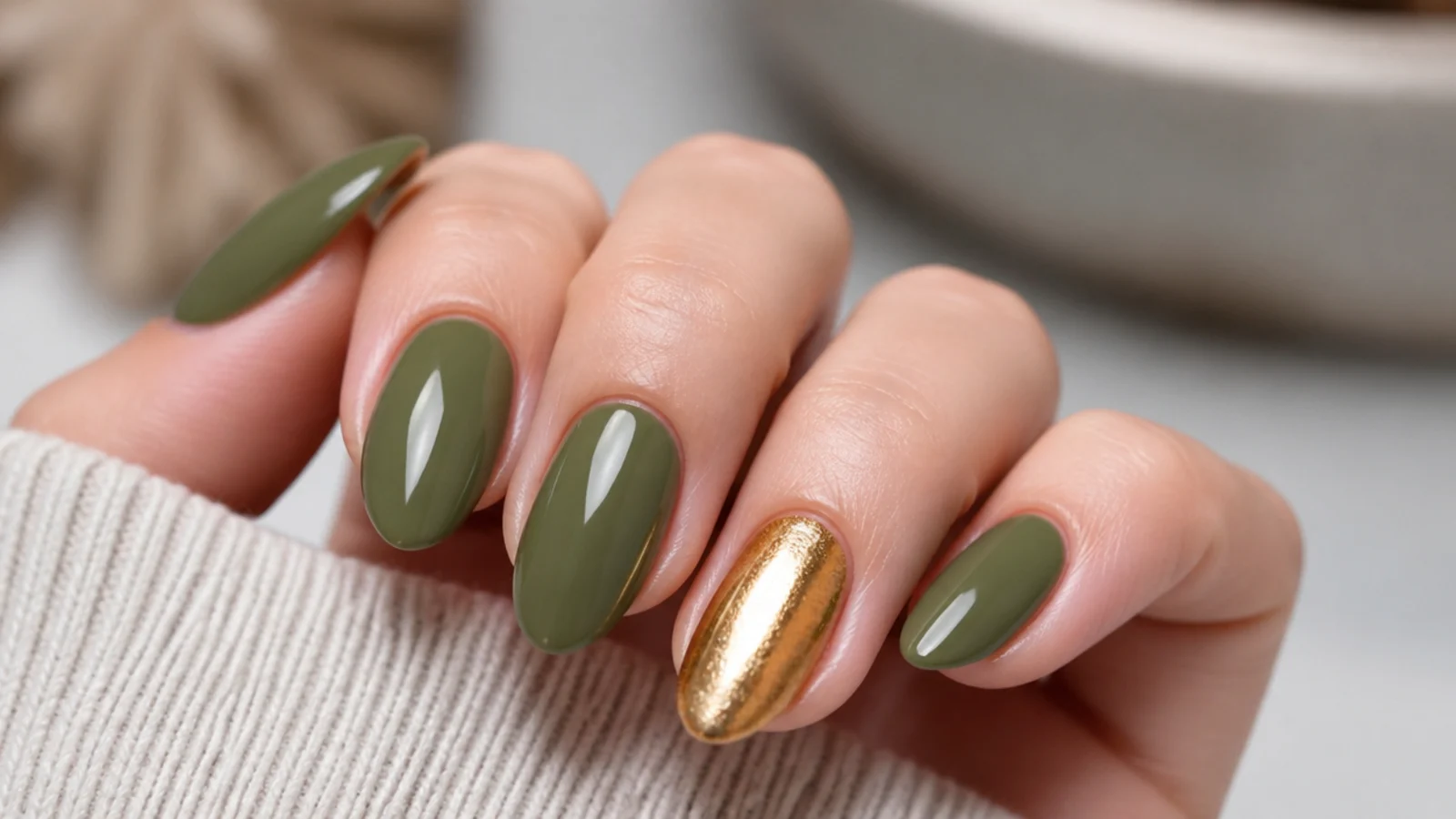 A single gold accent nail beside earthy olive green nails