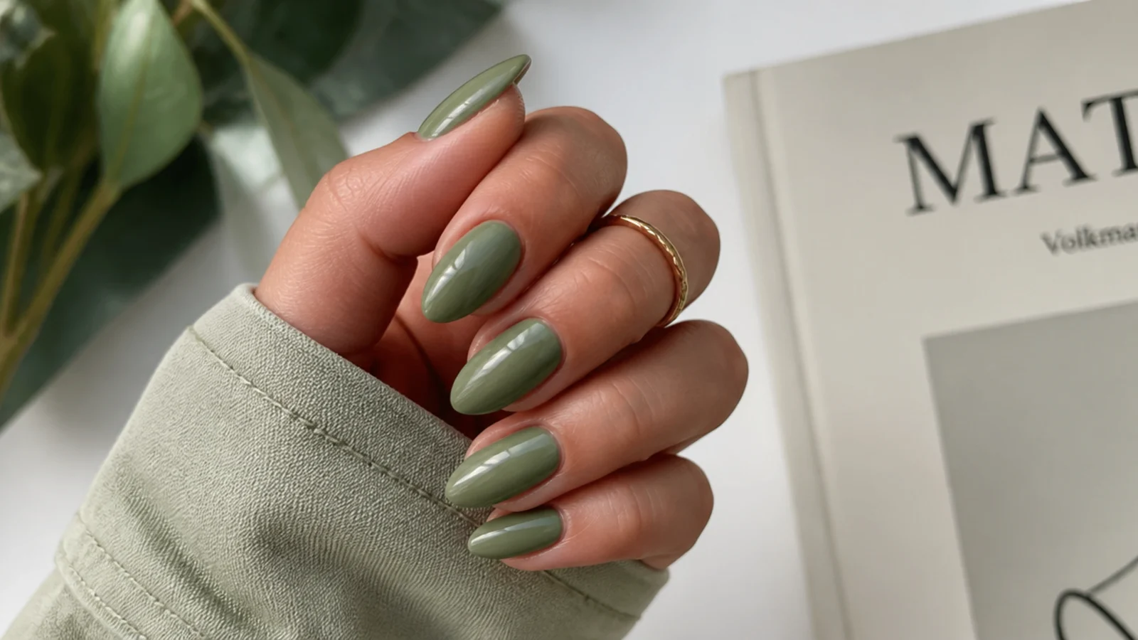 Soft light olive green nails on an almond shape with a glossy muted khaki finish