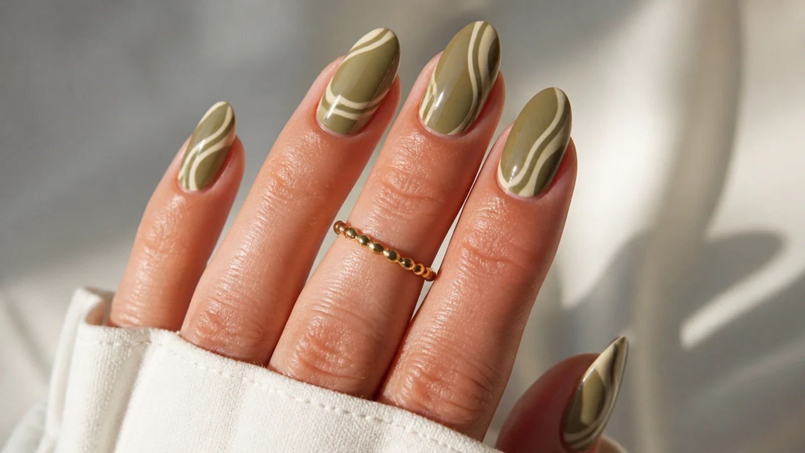 Warm olive almond nails with retro cream swirl lines