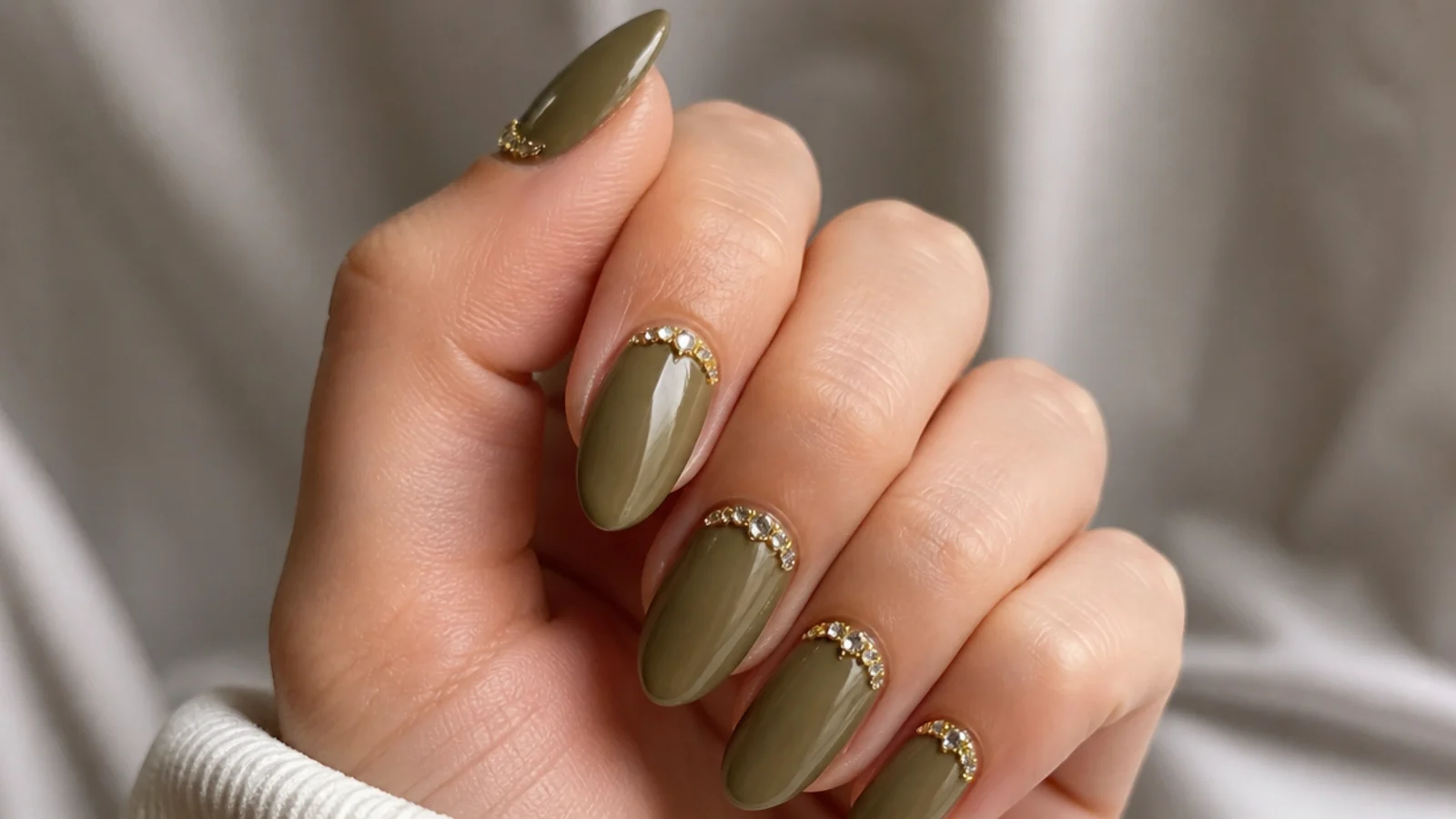 Warm olive almond nails with a gold rhinestone cuticle cuff