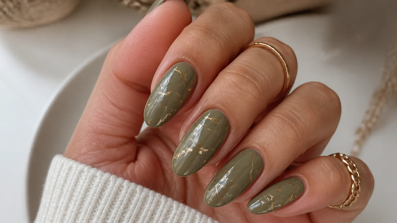 Warm olive almond nails with thin gold marble veins