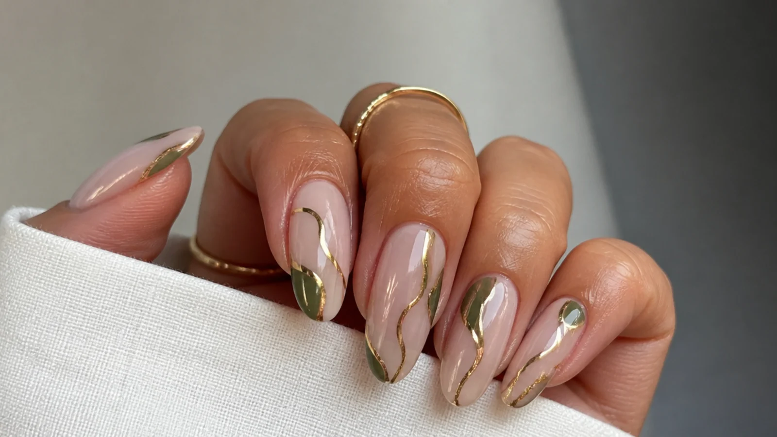 Nude nails with olive green and gold abstract swirl lines