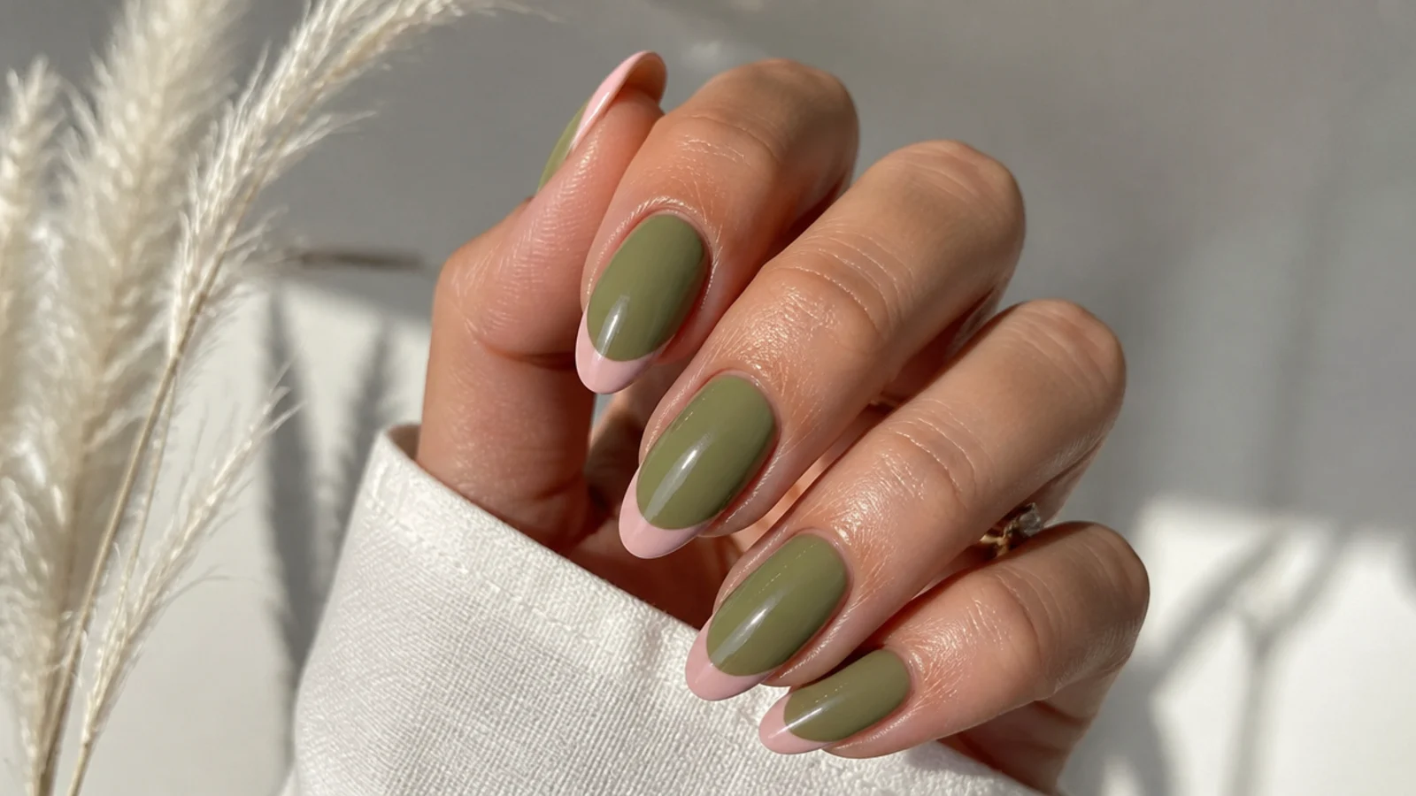 Sheer olive green nails with soft pink french tips on an almond shape
