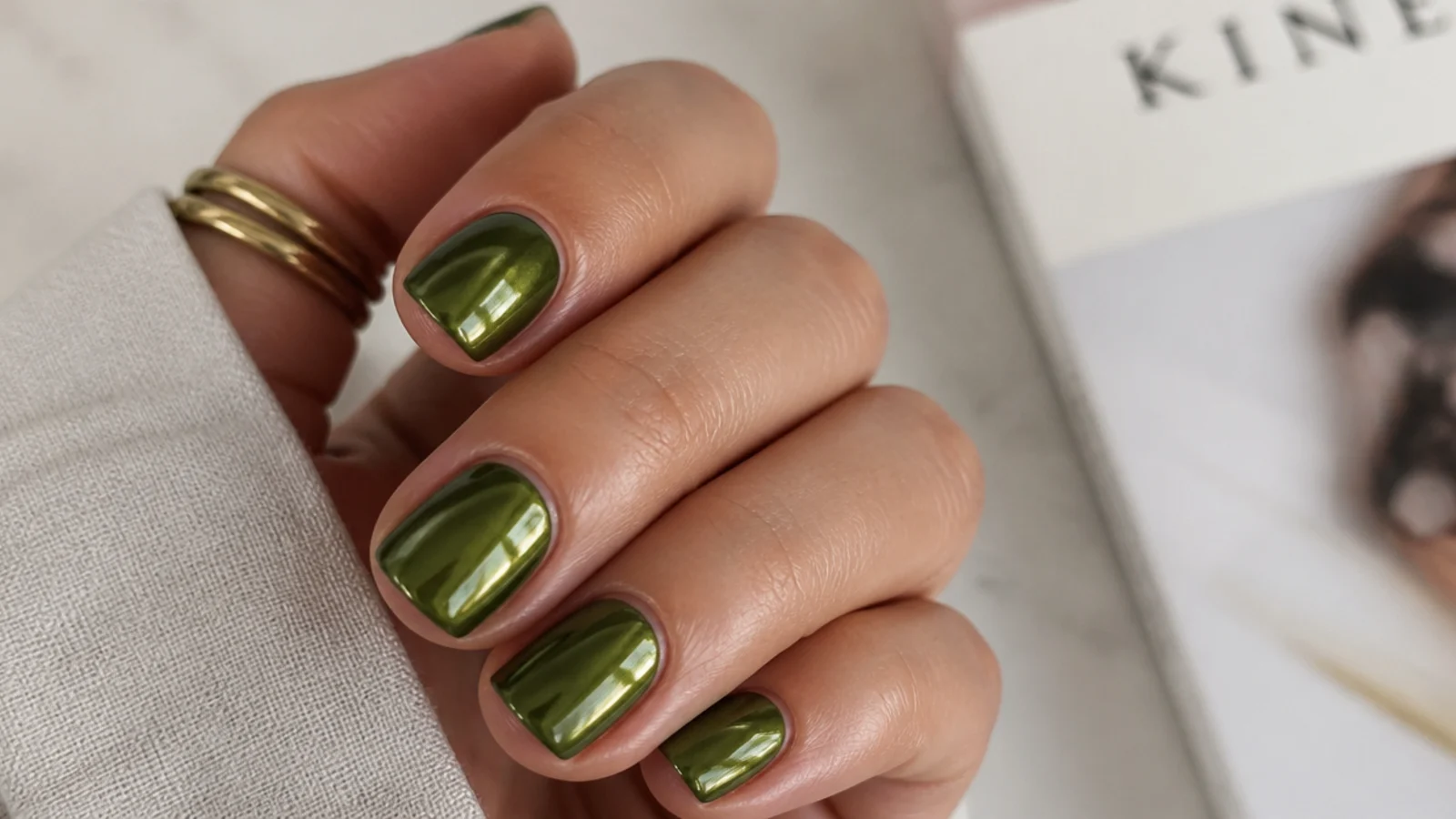 Short squoval olive green chrome nails on a neat everyday hand
