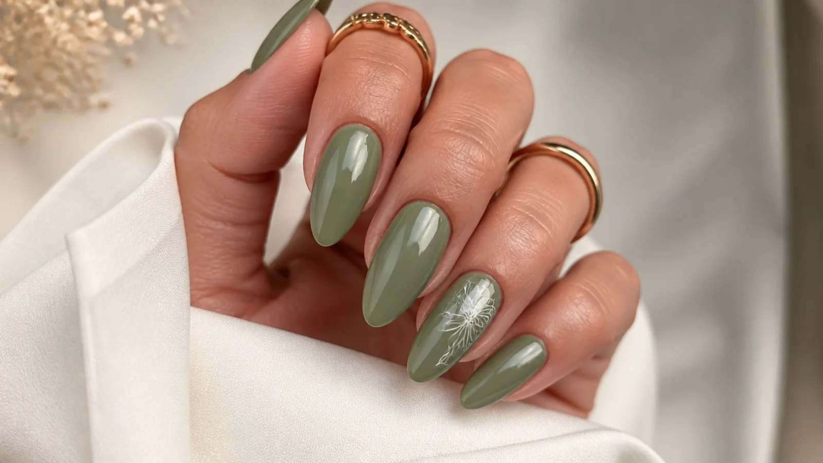 Glossy muted olive green almond nails on a warm skin tone