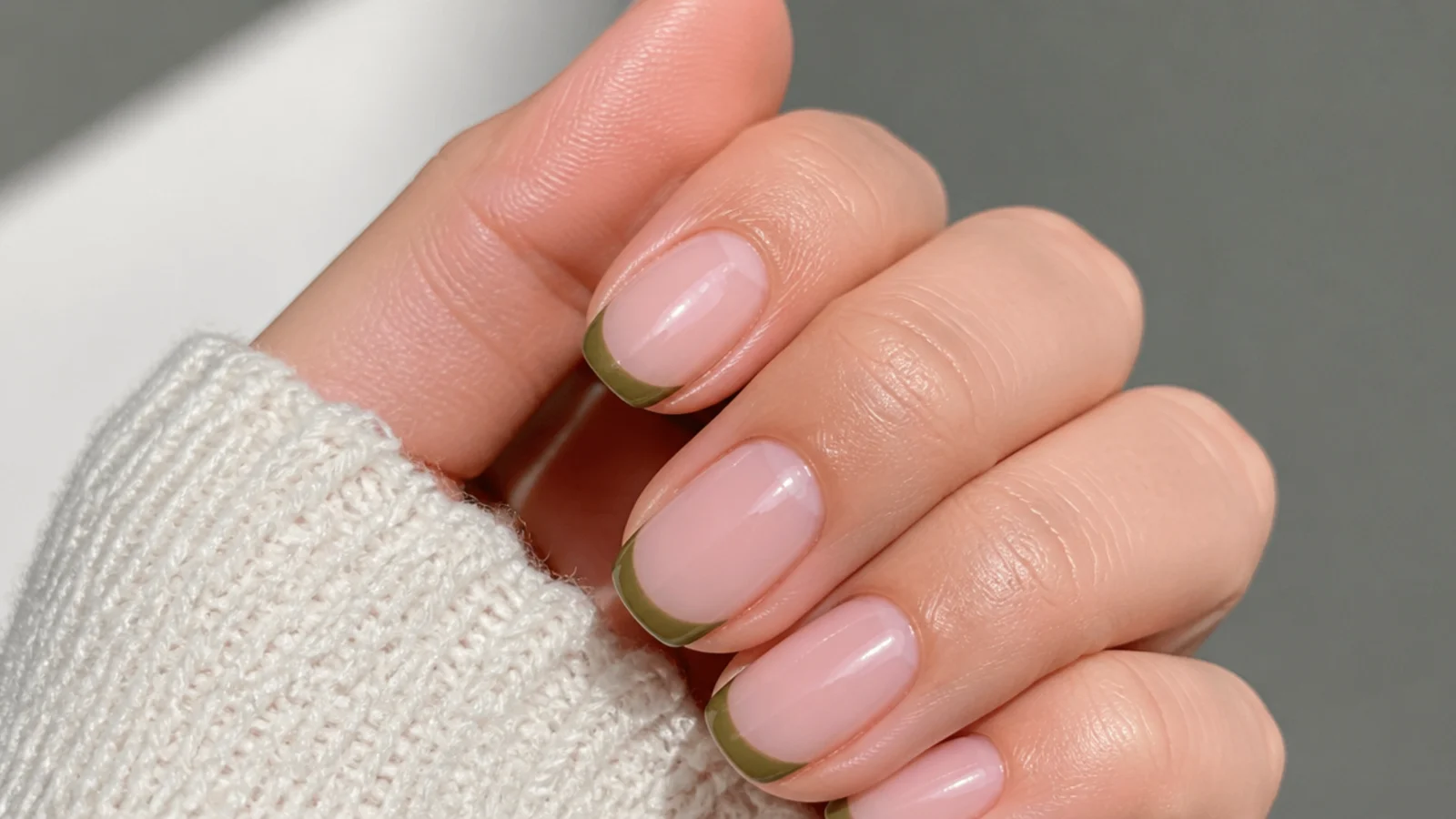 Sheer nude nails with clean olive green french tips