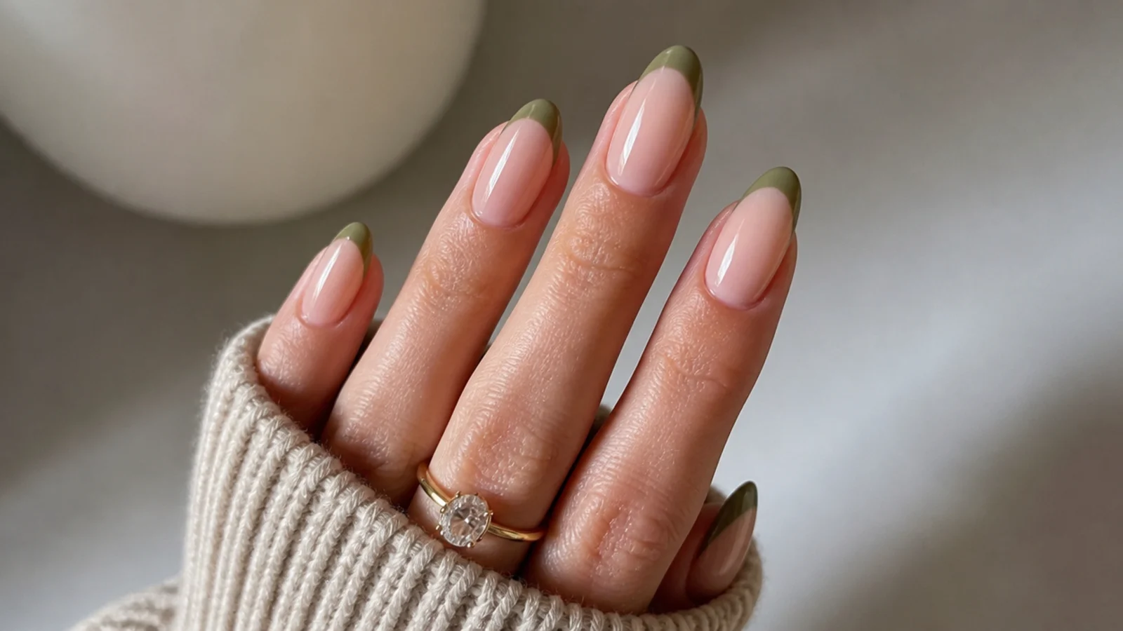 Thin muted olive green french tips over a sheer nude almond base