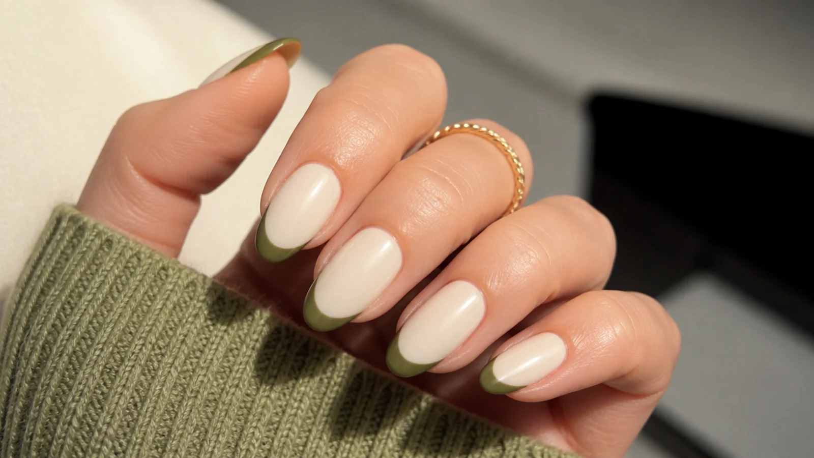 Olive green french tips over an opaque cream base on almond nails