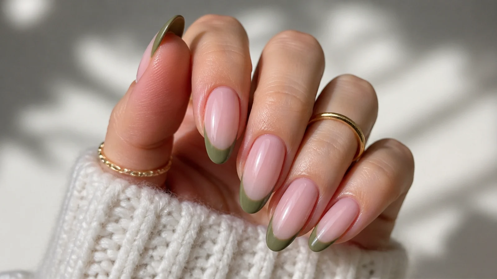 Olive green french tips over a soft blush pink base on almond nails
