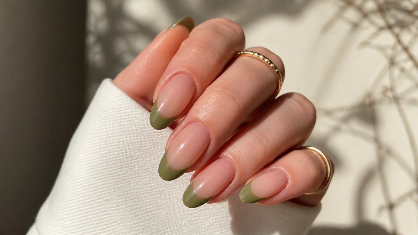 Muted olive green french tip nails on an almond shape over a nude base