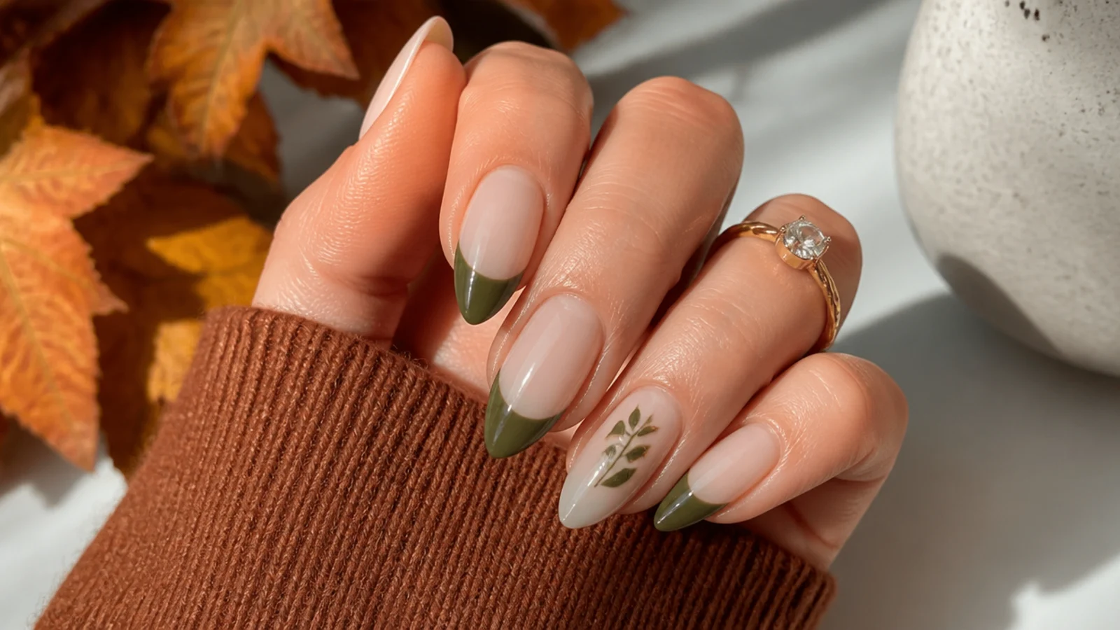 Olive green french tip nails styled for a fall setting with warm tones