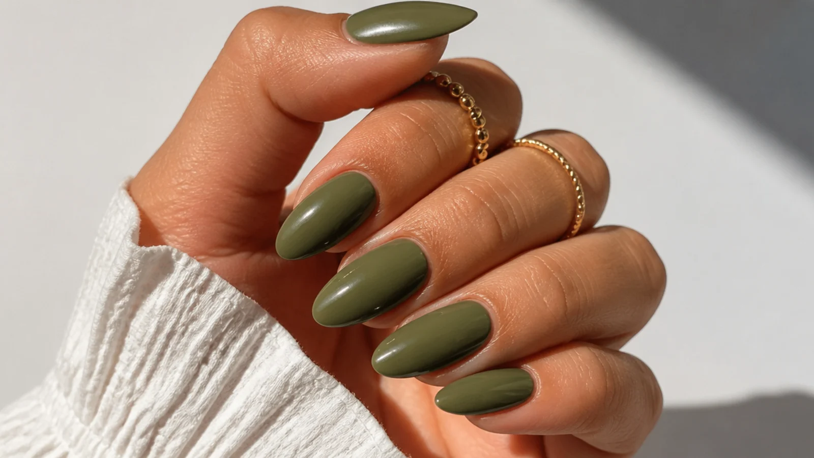 Almond nails in a solid warm-muted olive green over tan skin