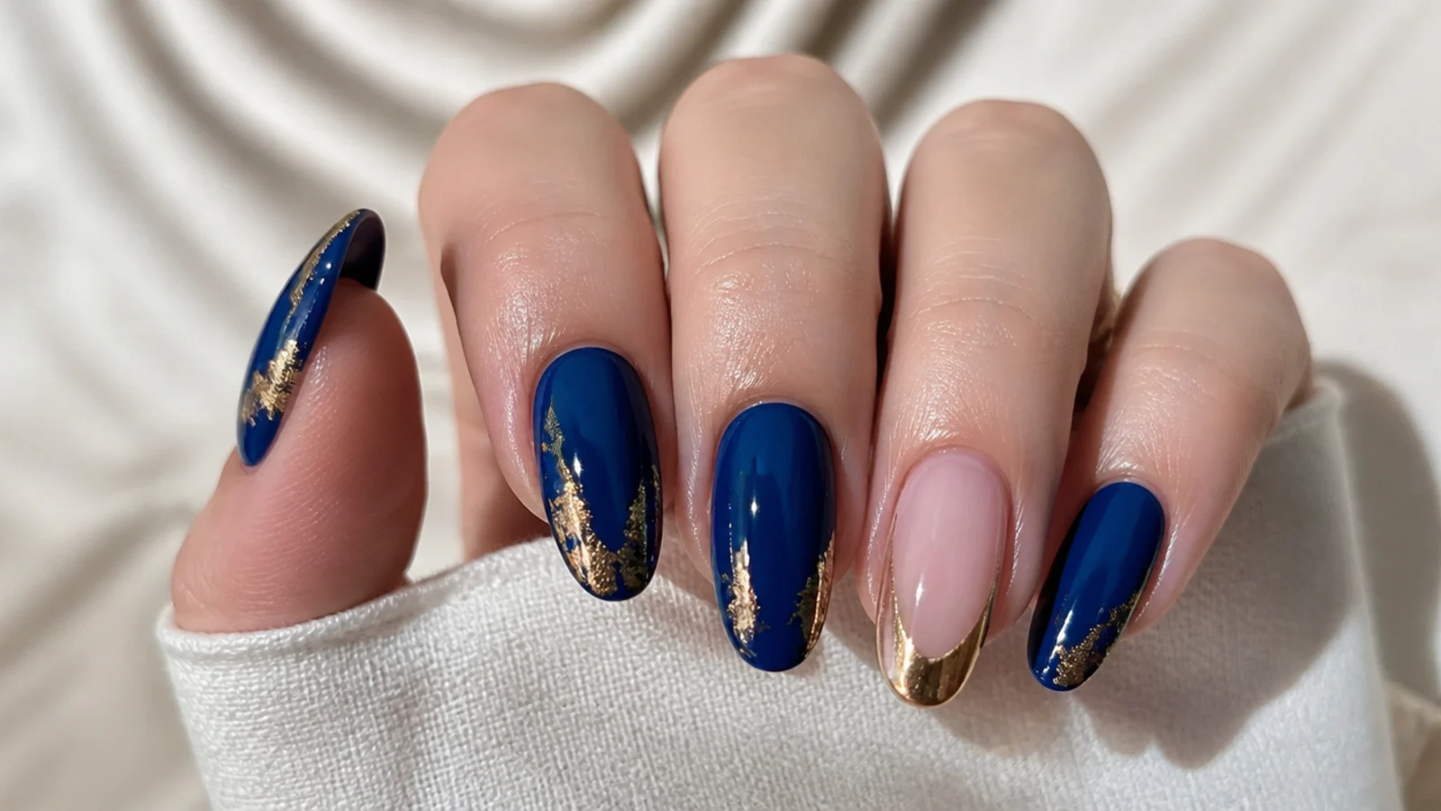 Royal blue nails with gold foil accents and a gold-tipped accent nail