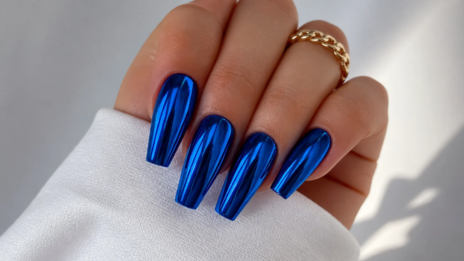 Full mirror chrome royal blue nails reflecting light on a coffin shape