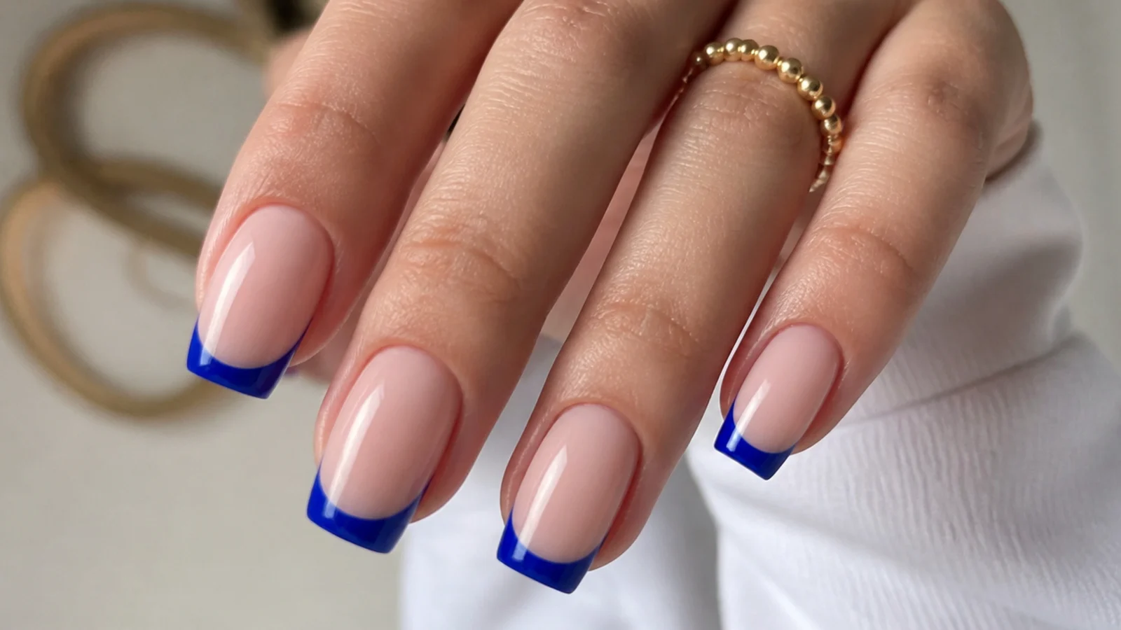 Nude nails with crisp royal blue french tips on a squoval shape