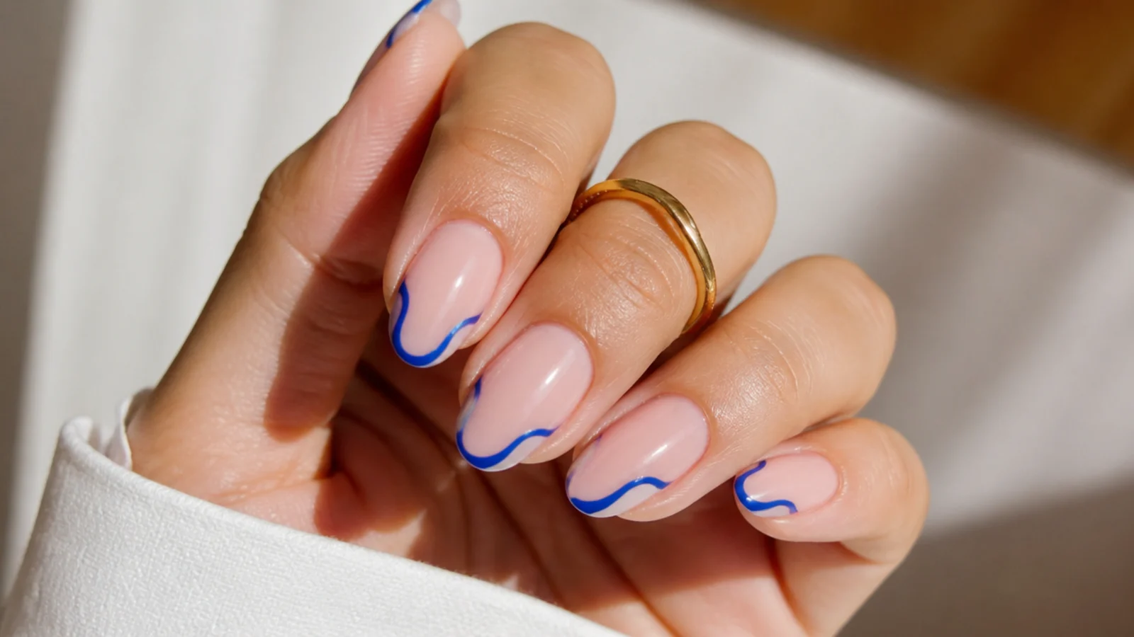 Nude nails with wavy royal blue swirl french tips
