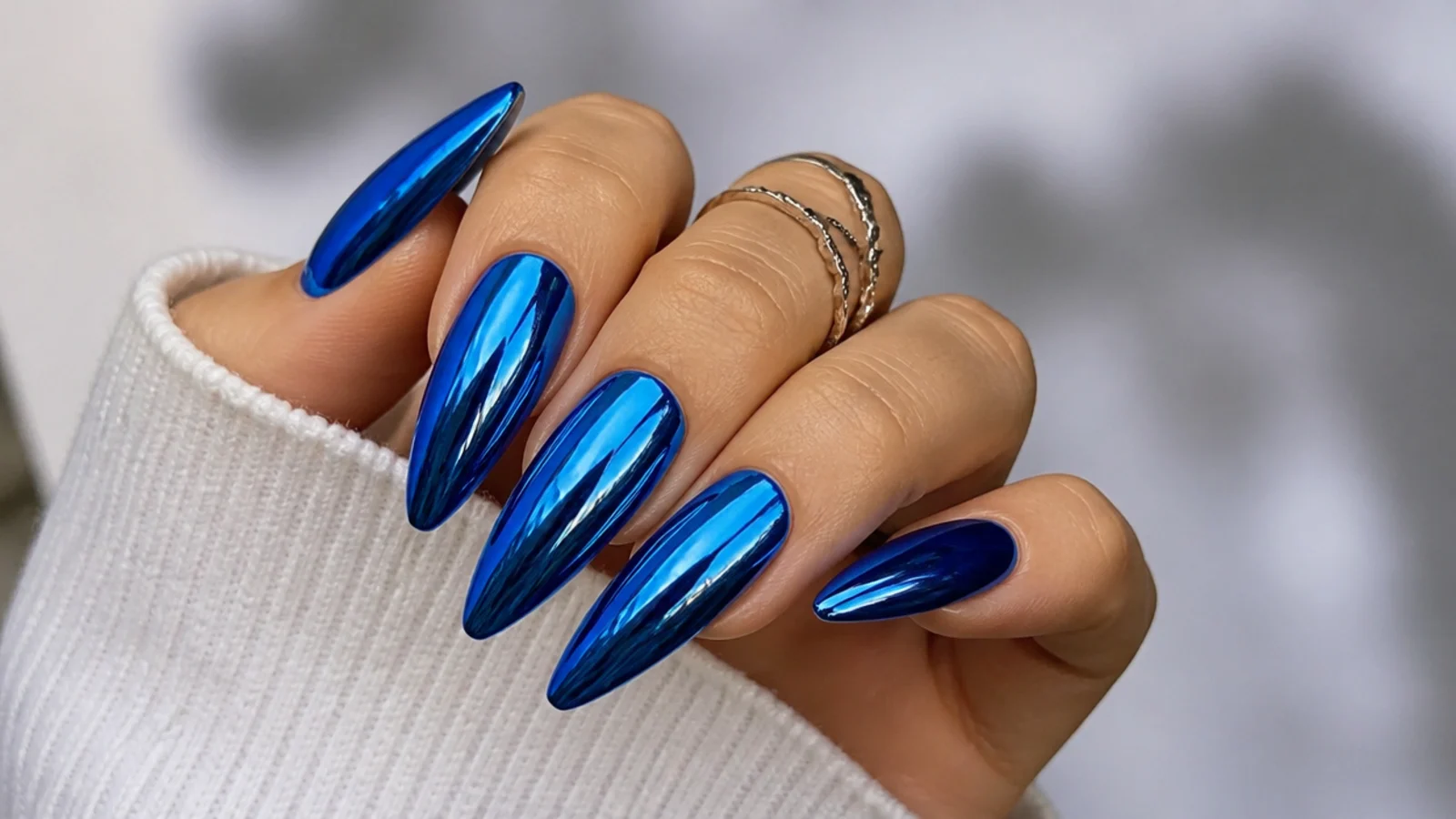 Long royal blue stiletto nails with a blue chrome mirror finish