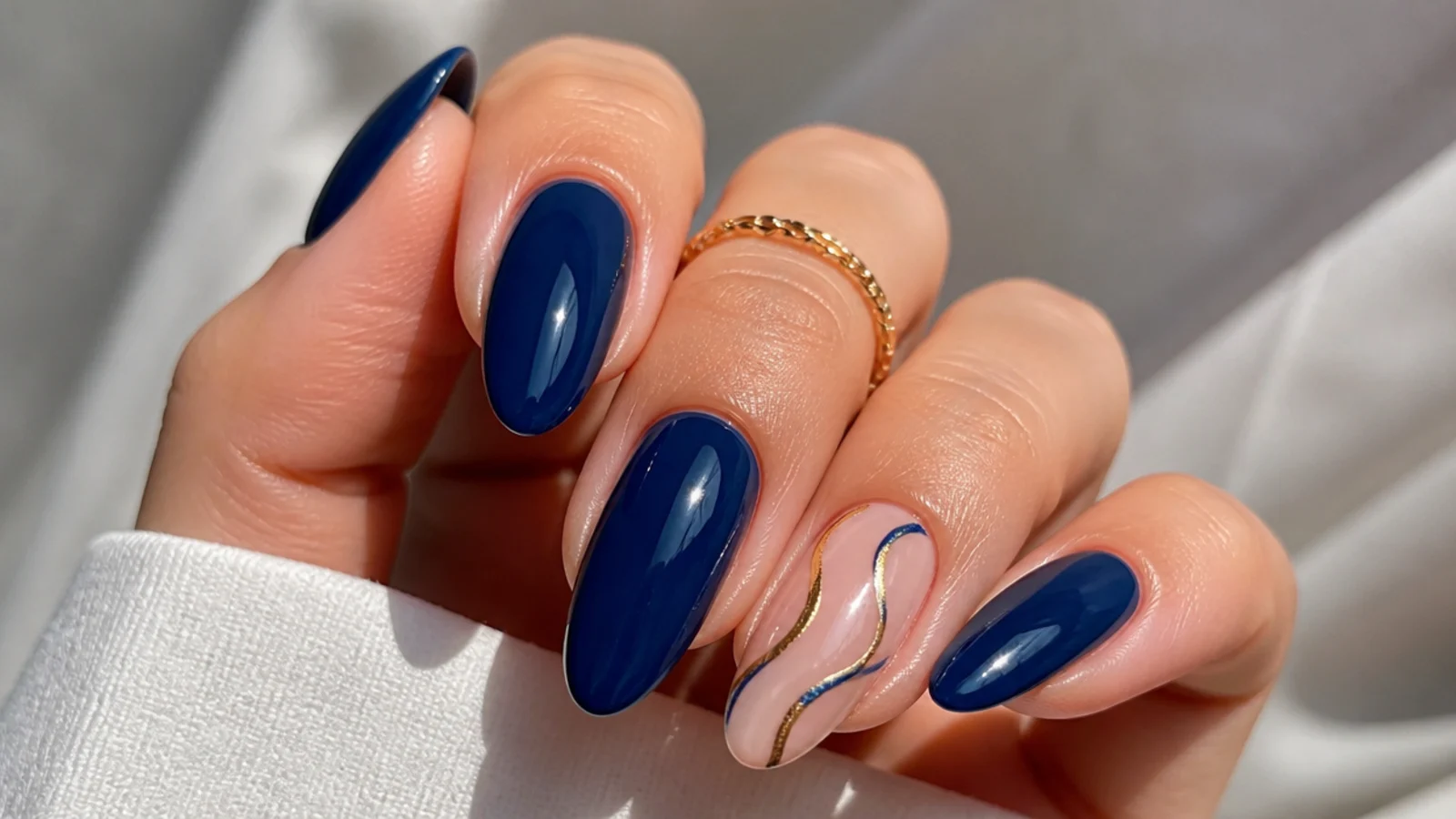 A gold-lined accent nail beside solid royal blue gel nails
