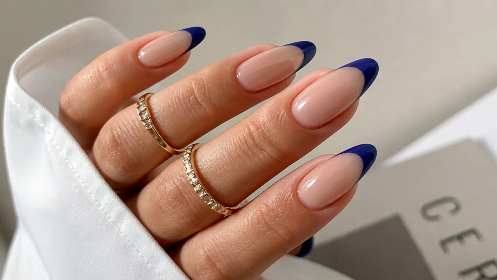 Nude acrylic nails with royal blue french tips on almond nails